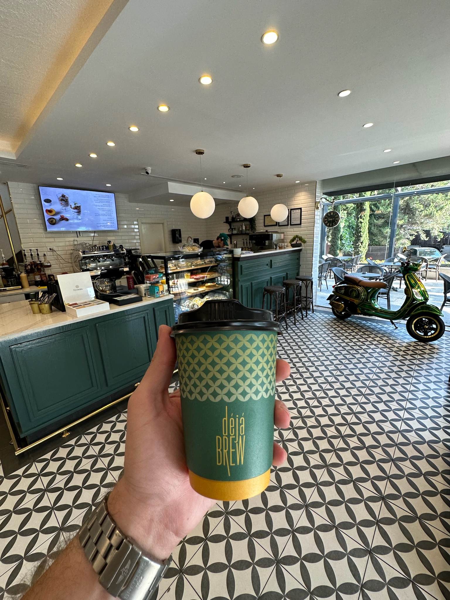 Inside Deja Brew Abdoun — green counter, pastry case and the signature green Vespa