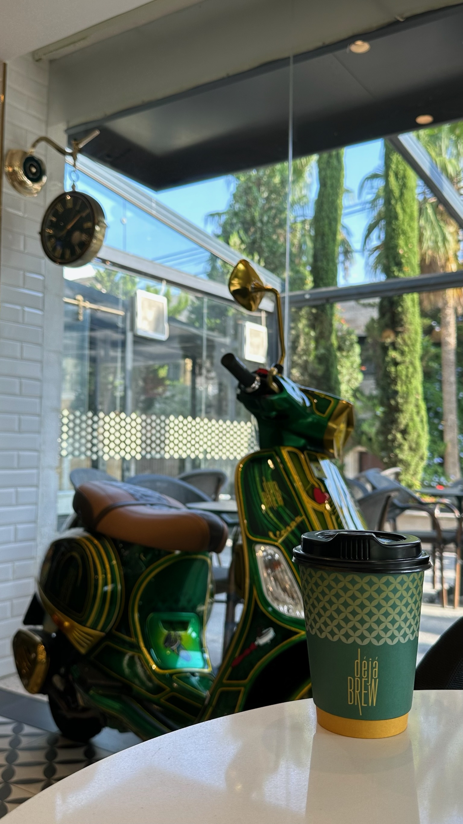Deja Brew cup on a table in the Abdoun café with the signature green Vespa behind