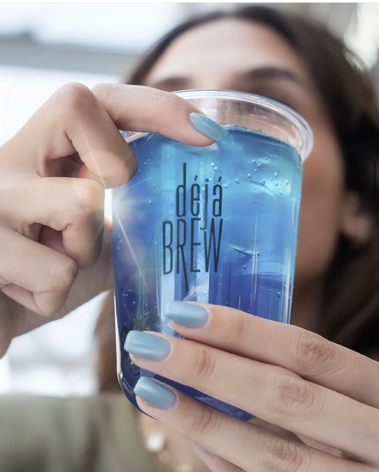 Guest sipping a signature blue iced drink in a Deja Brew cup, Amman